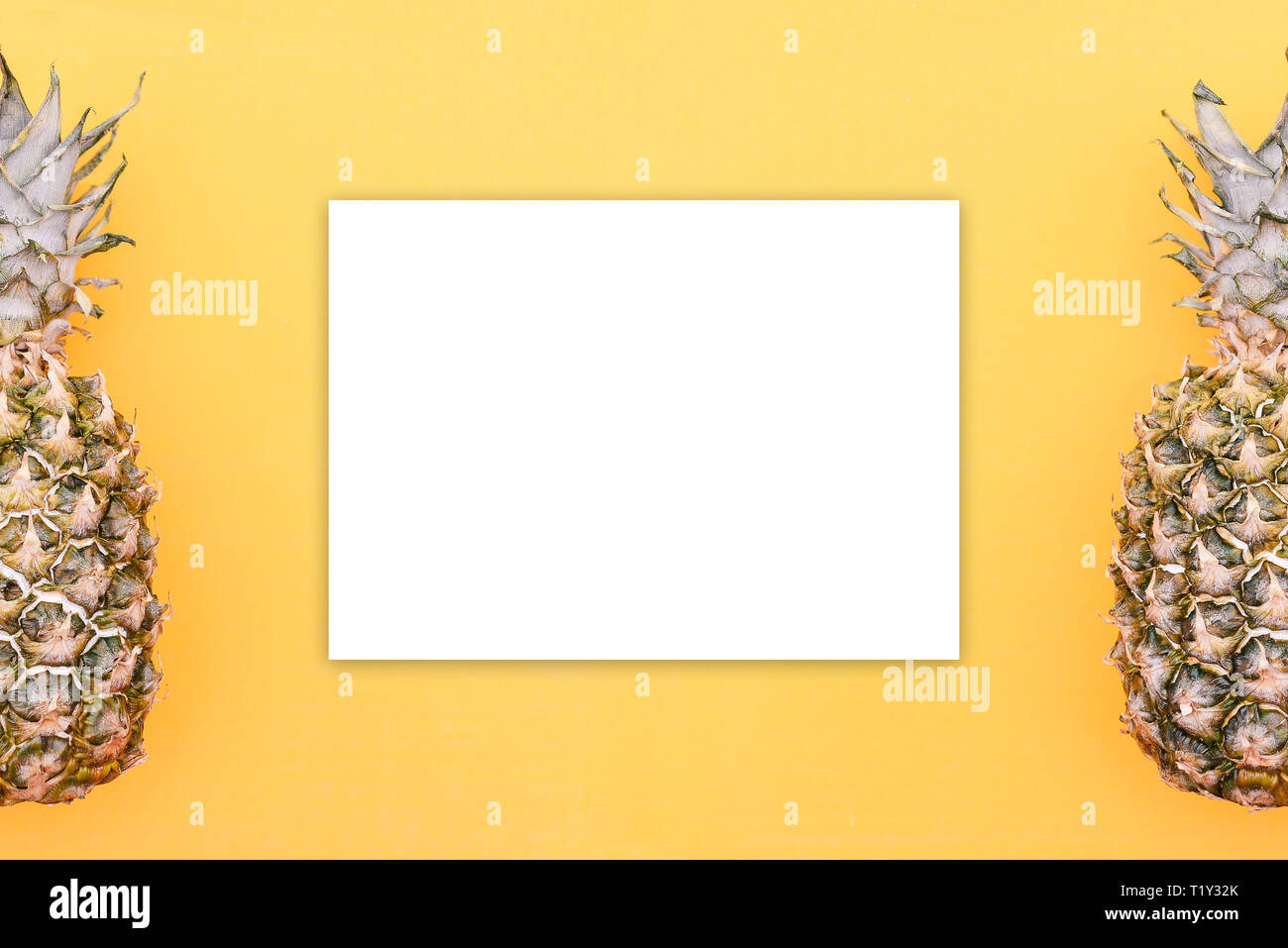 Pineapples lie on the edges of the orange background. In the center is a white blank sheet for writing text. Template on the theme of health or health Stock Photo