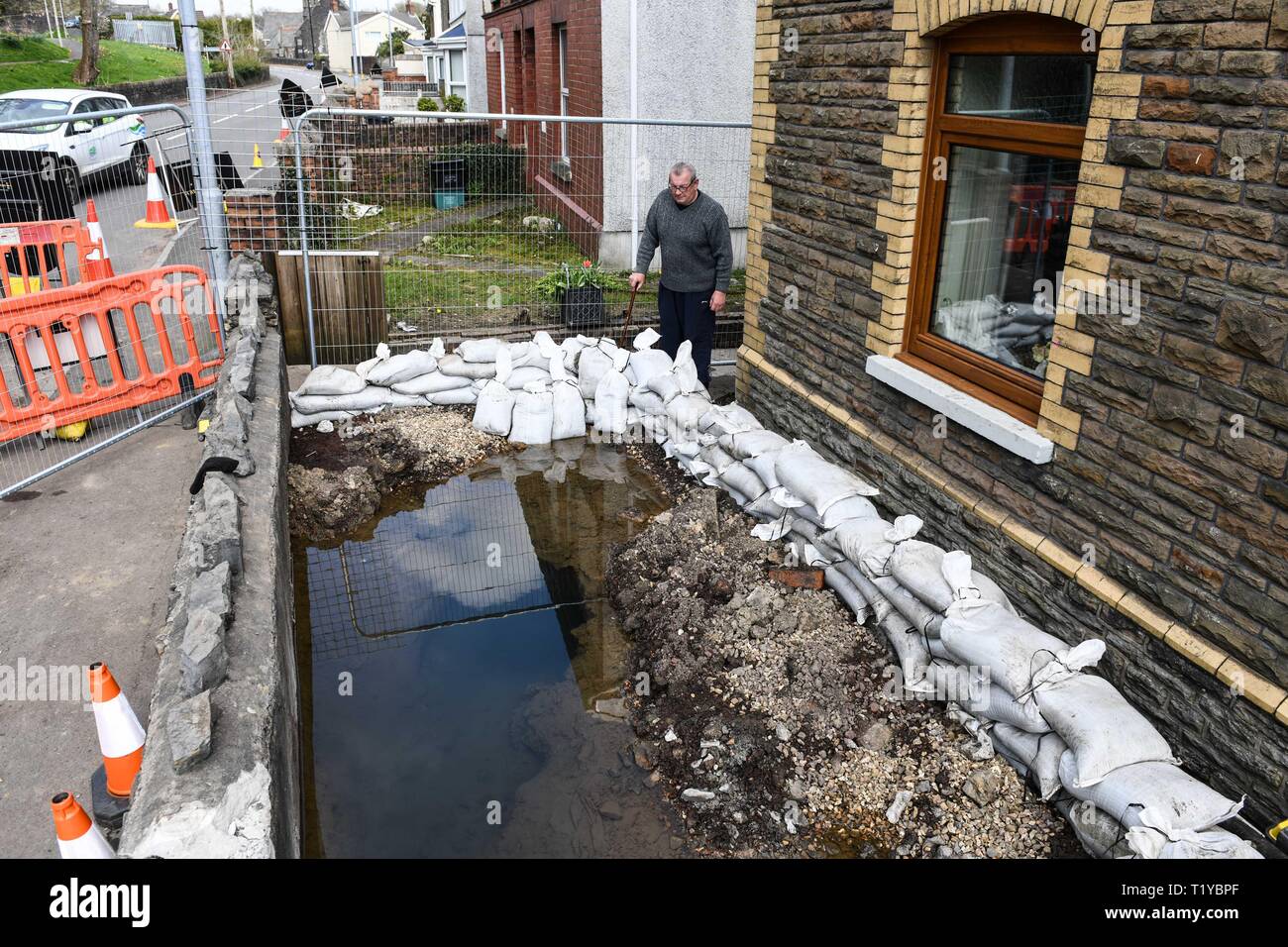 Swansea Valley, South Wales, UK. 29th March 2019 Pictured is Alun Lewis from the small village of Ystalyfera near Swansea, who awoke to a thermal spring which magically appeared in the front garden of his home. The source of the water cannot be found, although it is believed to be flowing from and abandoned mine, close to the property. The day before the spring appeared, his wife was planting flowers in the garden of the home that they have lived in for over 40-years. Credit : Robert Melen/Alamy Live News Stock Photo