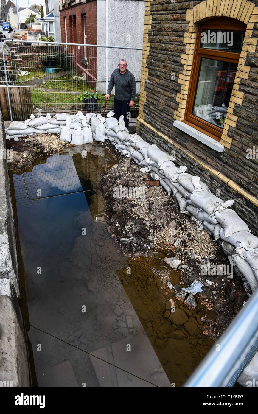 Swansea Valley, South Wales, UK. 29th March 2019 Pictured is Alun Lewsi from the small village of Ystalyfera near Swansea, who awoke to a thermal spring which magically appeared in the front garden of his home. The source of the water cannot be found, although it is believed to be flowing from and abandoned mine, close to the property. The day before the spring appeared, his wife was planting flowers in the garden of the home that they have lived in for over 40-years. Credit : Robert Melen/Alamy Live News Stock Photo