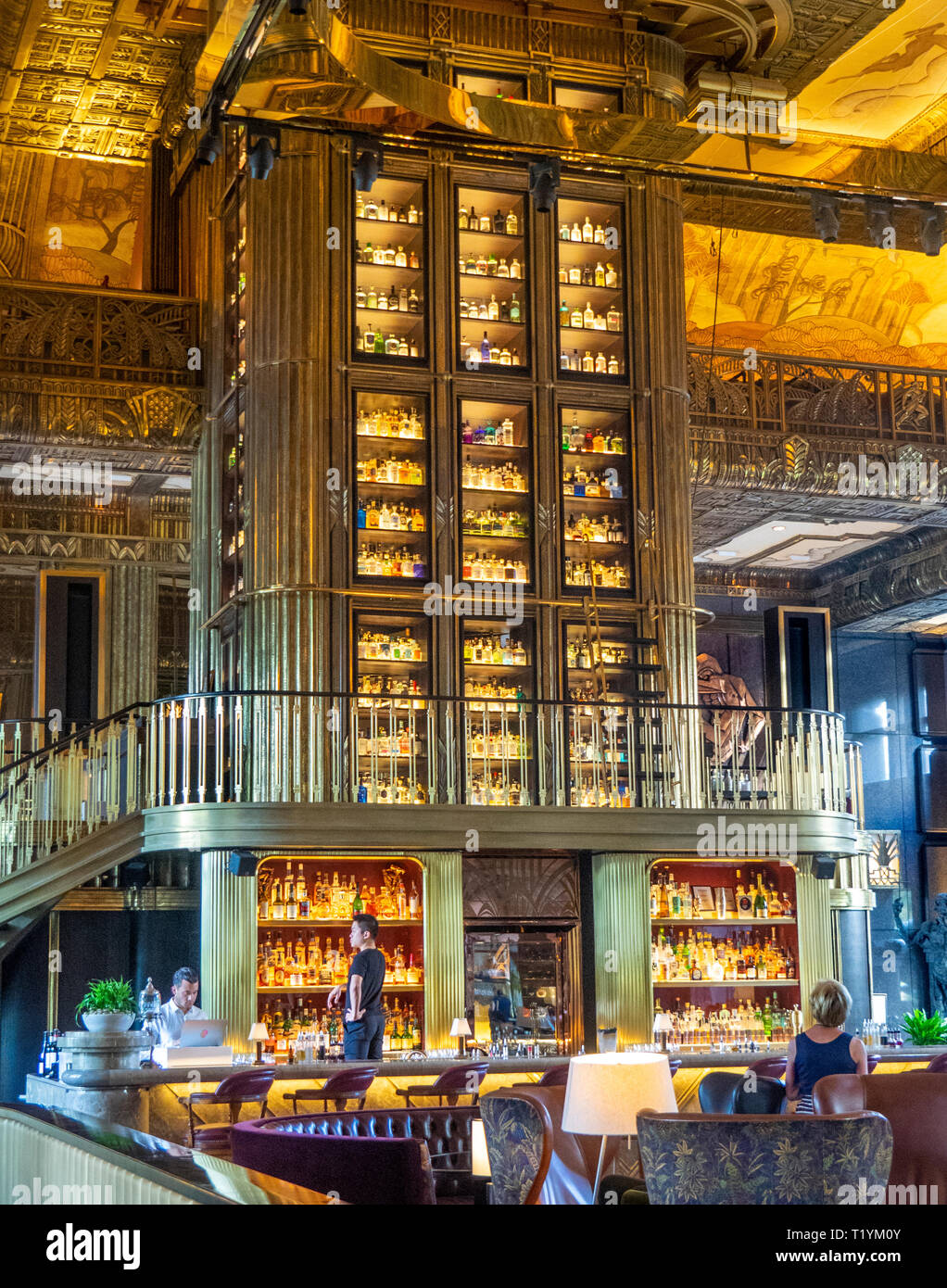 Tall cabinet or gin tower with glass and carved wooden columns the  centerpiece of the Atlas bar in the lobby of Parkview Square Singapore. Stock Photo