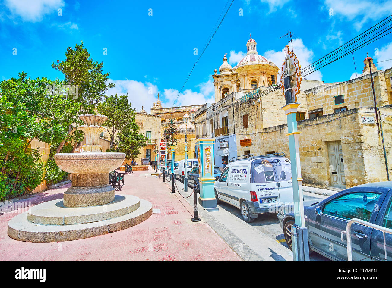 RABAT, MALTA - JUNE 16, 2018: The old stone fountain in tiny garden in College street with a view on the dome of St Paul Church, on June 16 in Rabat. Stock Photo