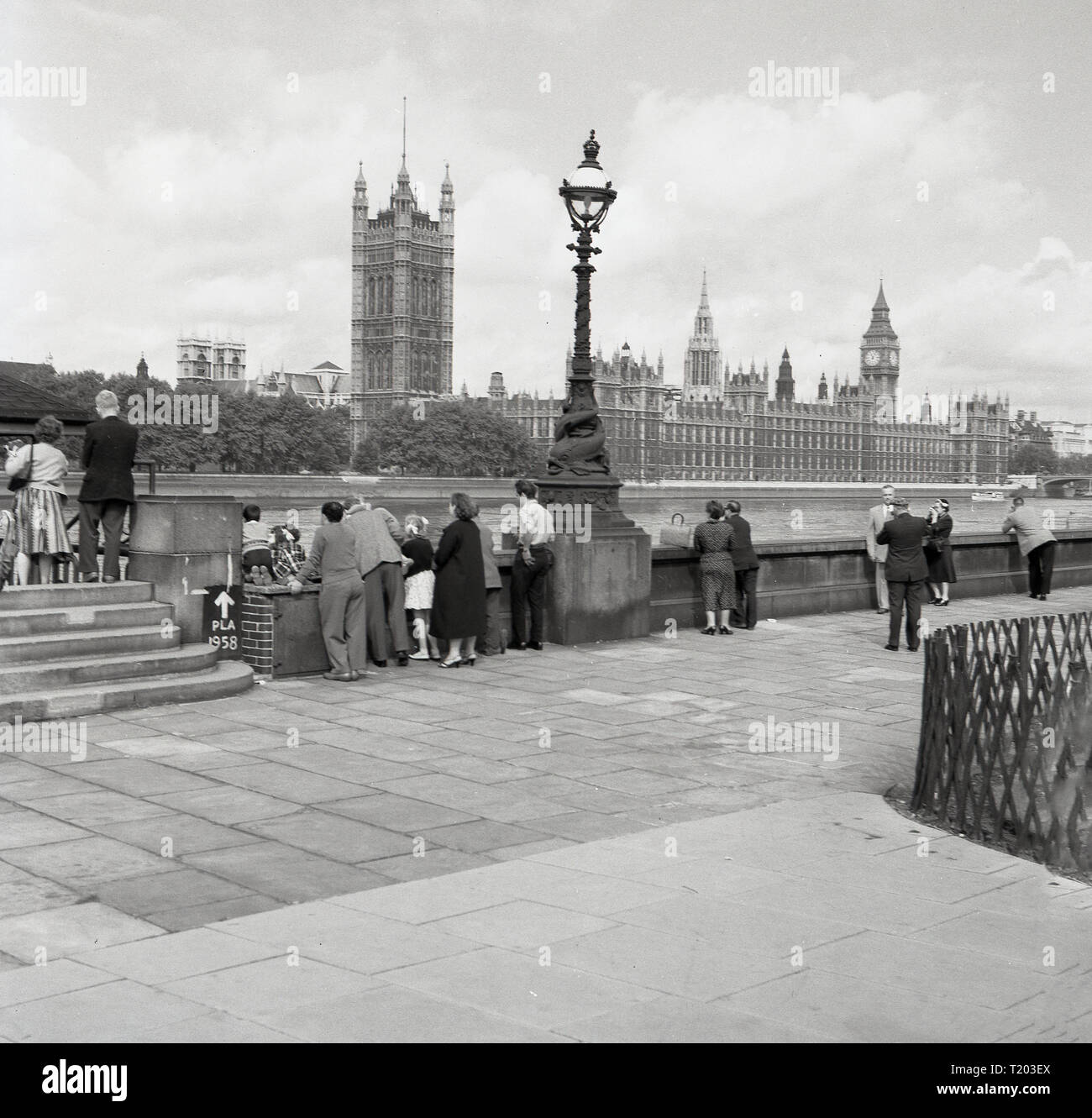 1960s, London, sight-seeing, visitors to the city standing on the southbank of the river Thames take in the view of the Palace of Westminster, the home of the two Houses of Parliament of the UK Government. Stock Photo