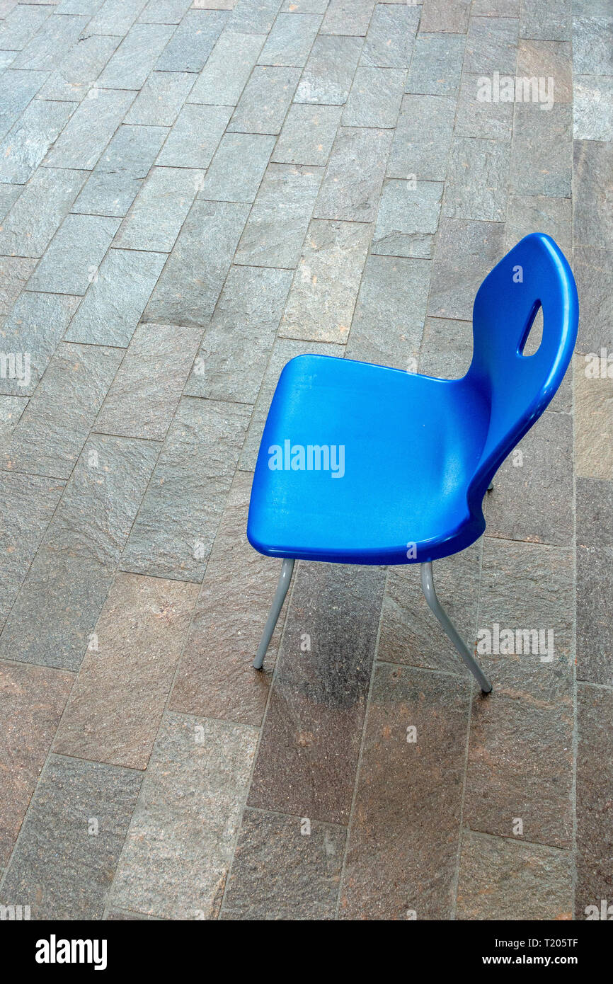 view looking down onto a single blue plastic stacking chair sitting ...