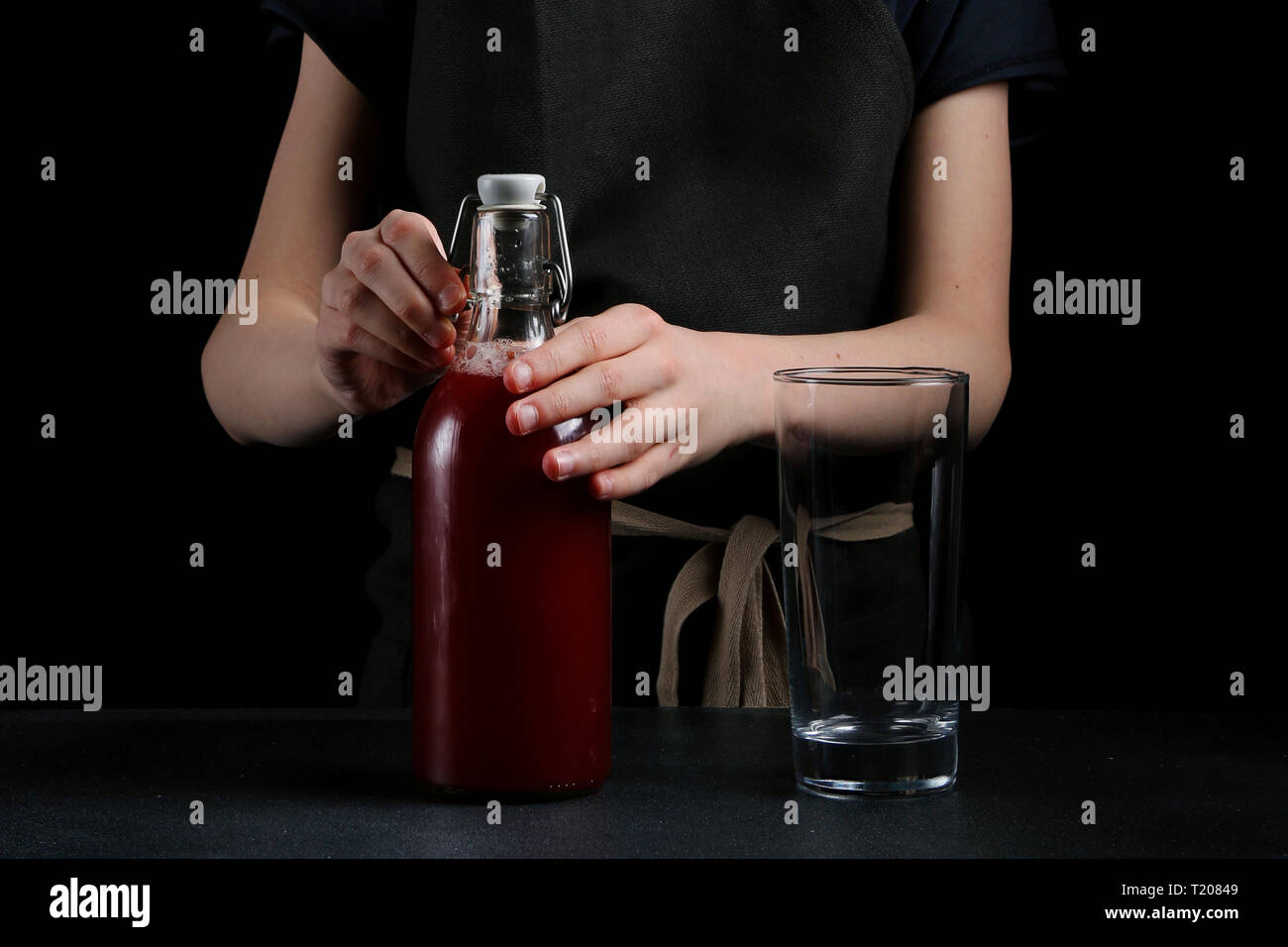 girl pouring juice in glass on dark background. summer drink concept