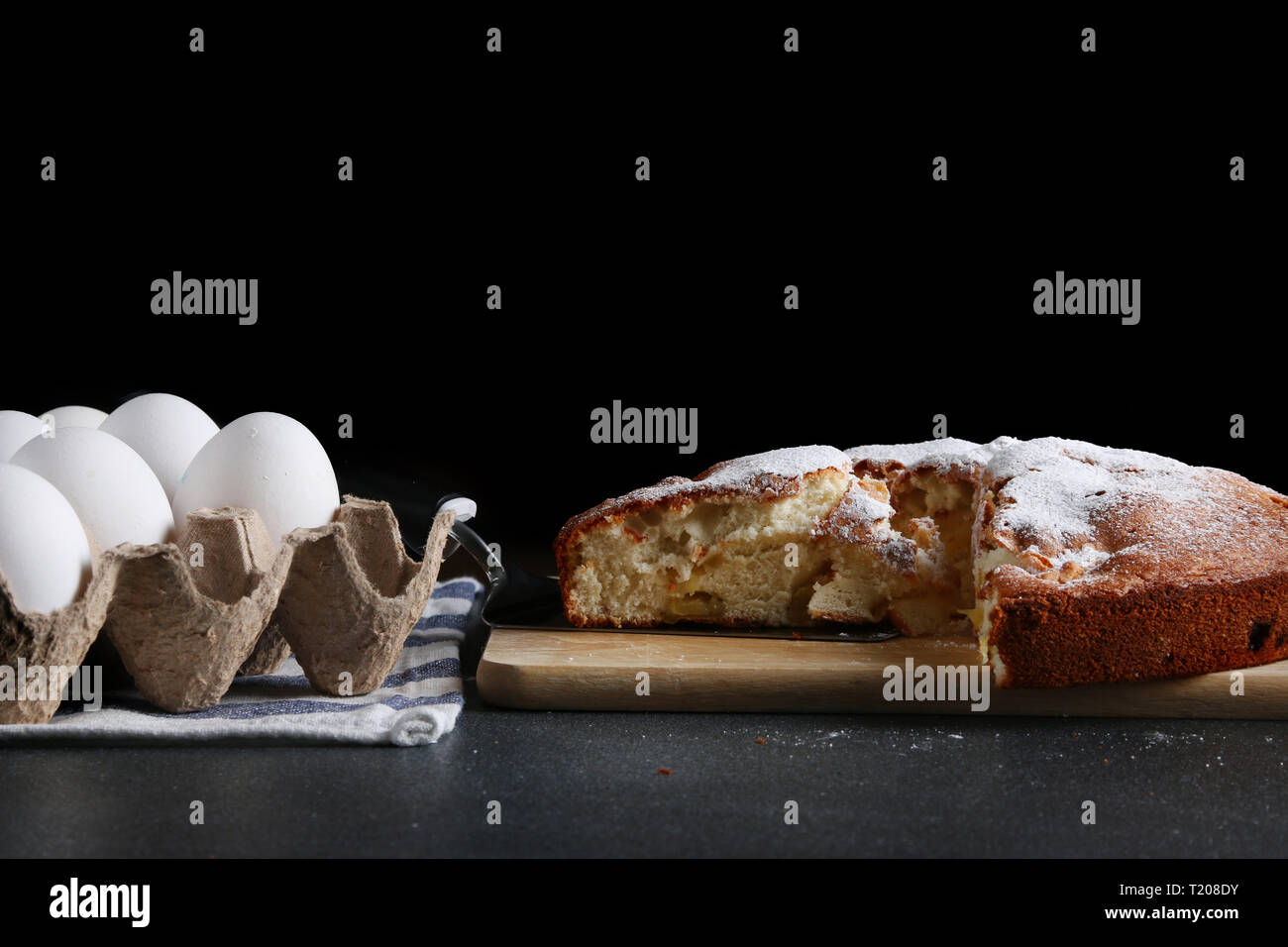 sliced pie and ingredients for making on dark background. Stock Photo