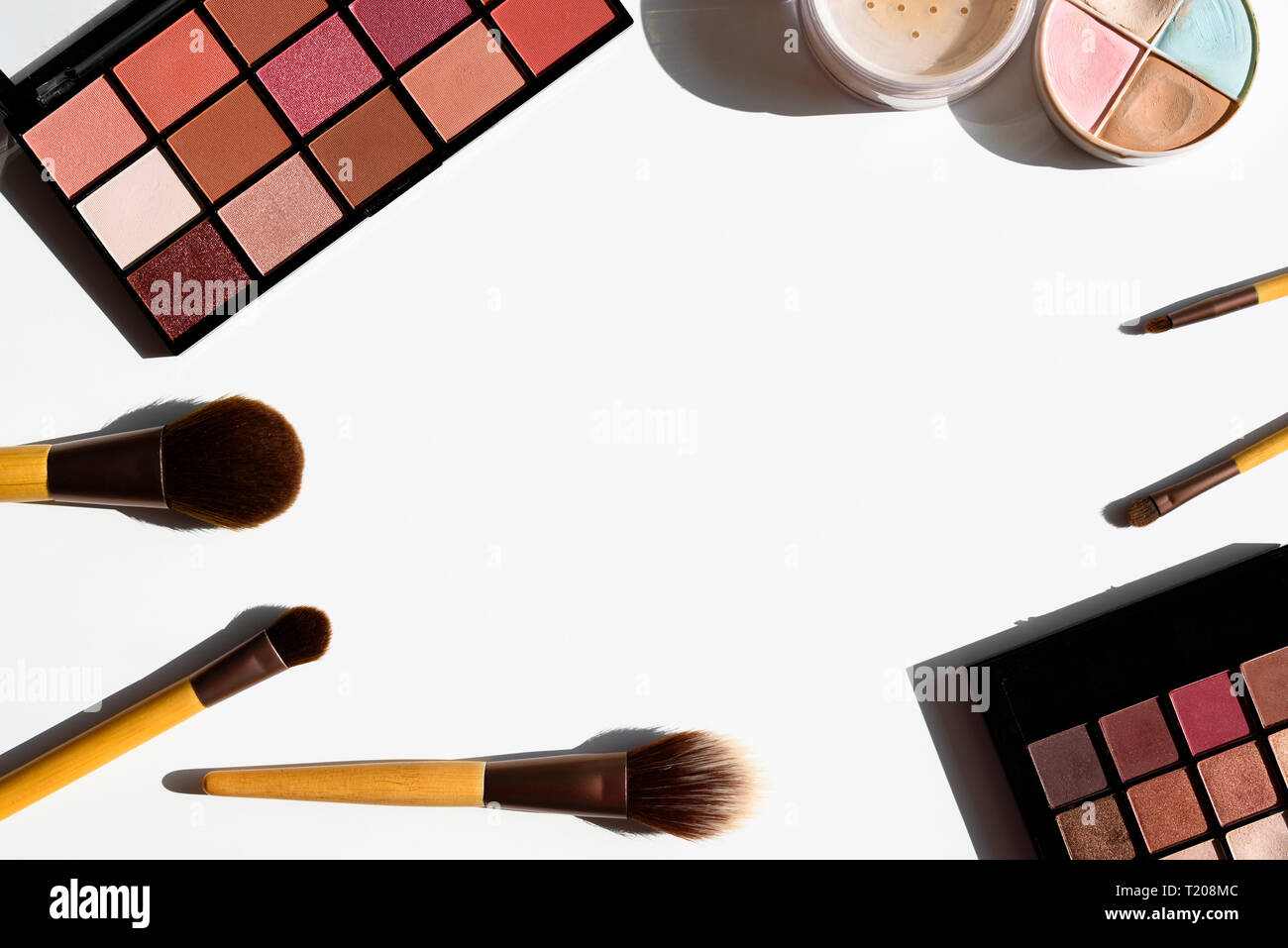 Bright arrangement of make up cosmetics and accessories. Eyeshadow palettes, powder, concealer and natural brushes with bamboo wood handles. Copy spac Stock Photo