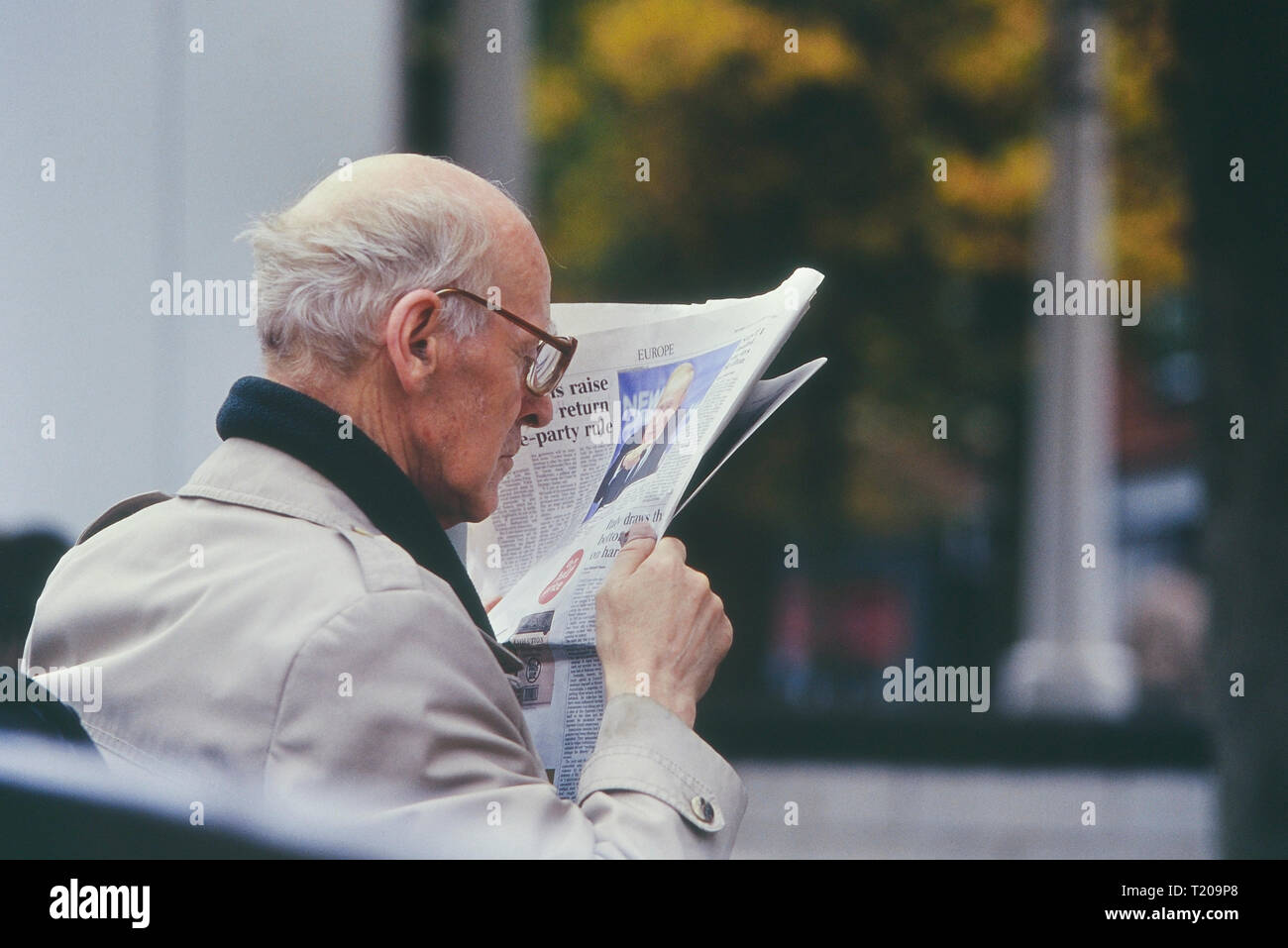 A mature man reading a newspaper up close to his face, England, UK Stock Photo