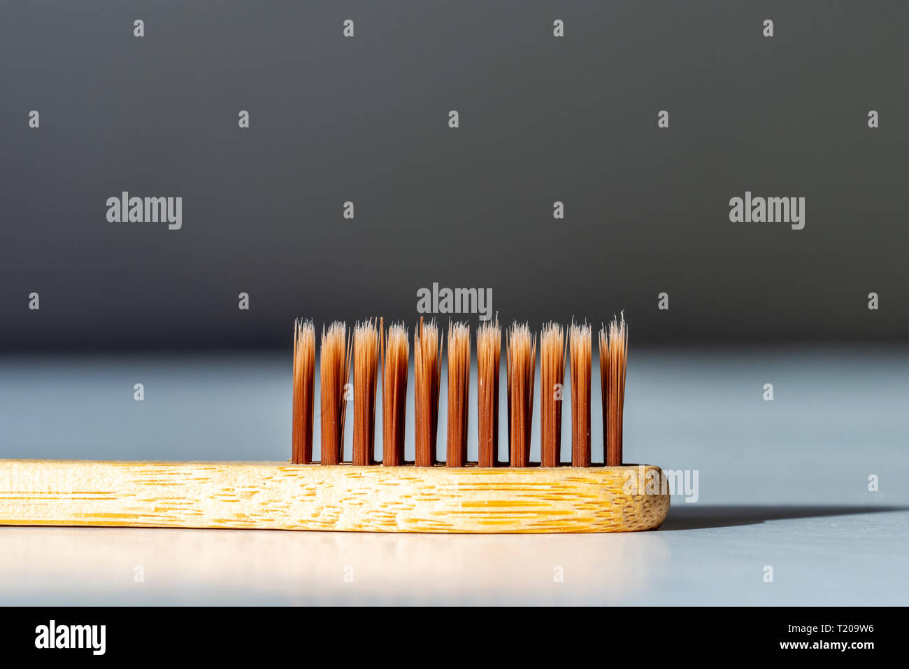 Bamboo tooth brush on white surface under bright sun light. Stock Photo