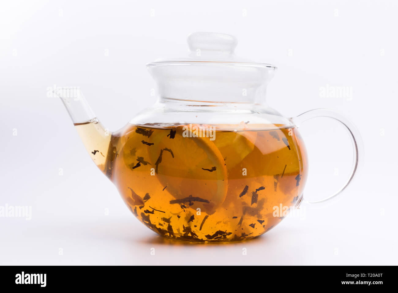 Glass teapot with herbal tea nad fresh orange isolated on white