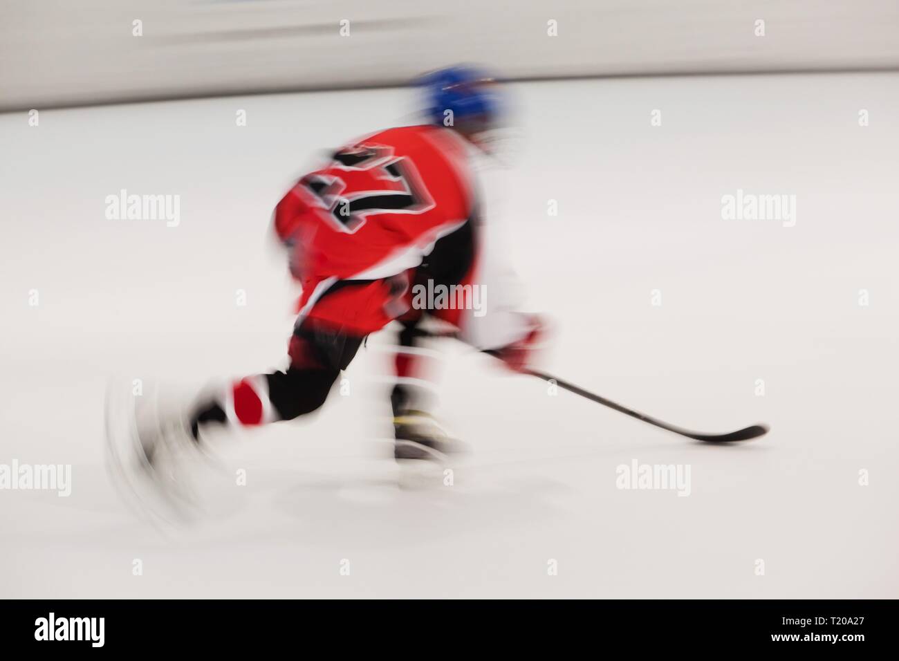 Young hockey player in red dress with number 27 in movement, blurry