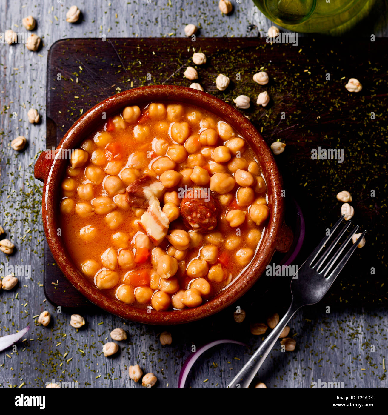 high angle view of an earthenware casserole with garbanzos a la riojana, a spanish chickpeas stew, on a wooden chopping board placed on a rustic woode Stock Photo