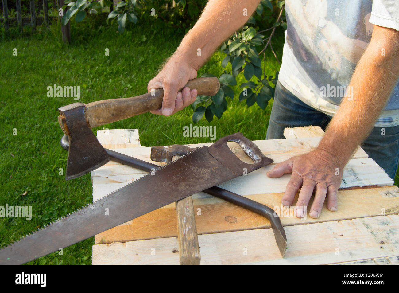 https://c8.alamy.com/comp/T20BWM/man-holding-the-axe-working-with-construction-tools-in-his-garden-T20BWM.jpg