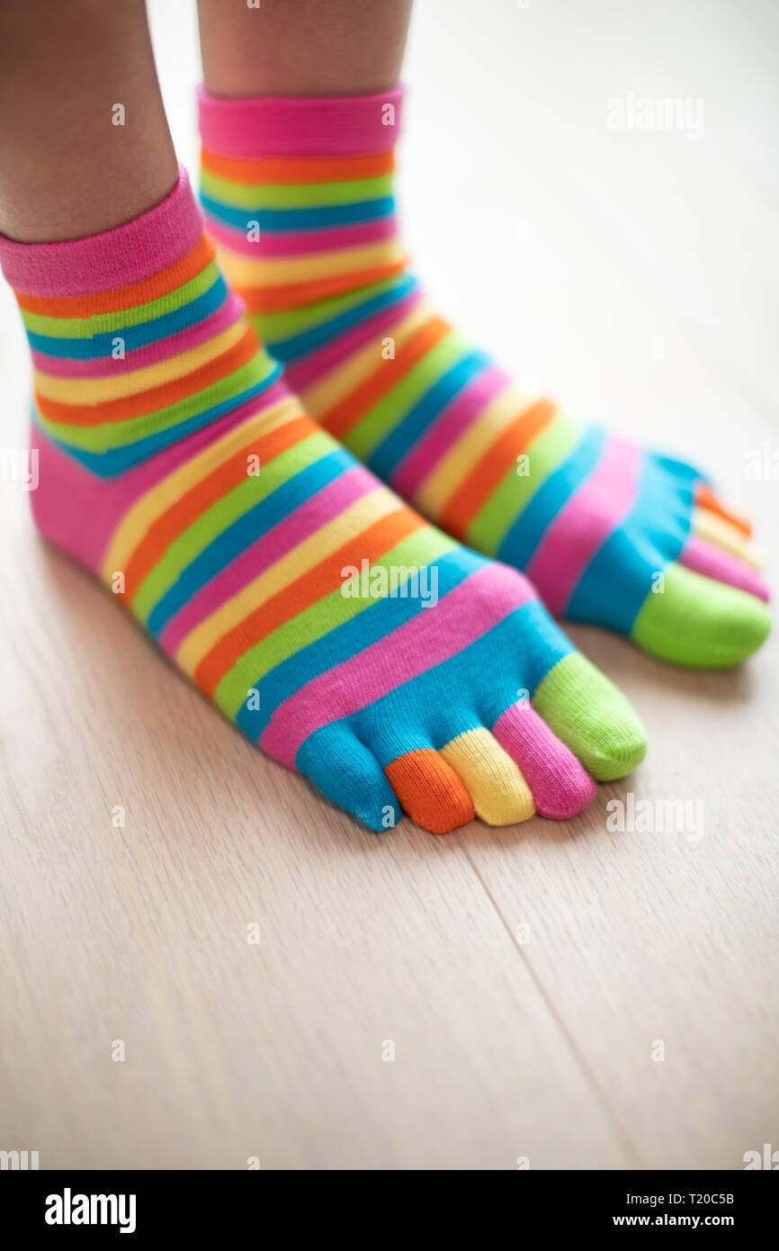 Close Up Of Woman Wearing Brightly Colored Socks On Feet Standing On Wooden Floor Stock Photo