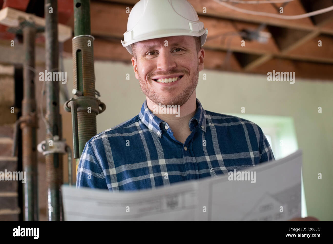 Portrait Of Architect Inside House Being Renovated Studying Plans Stock Photo