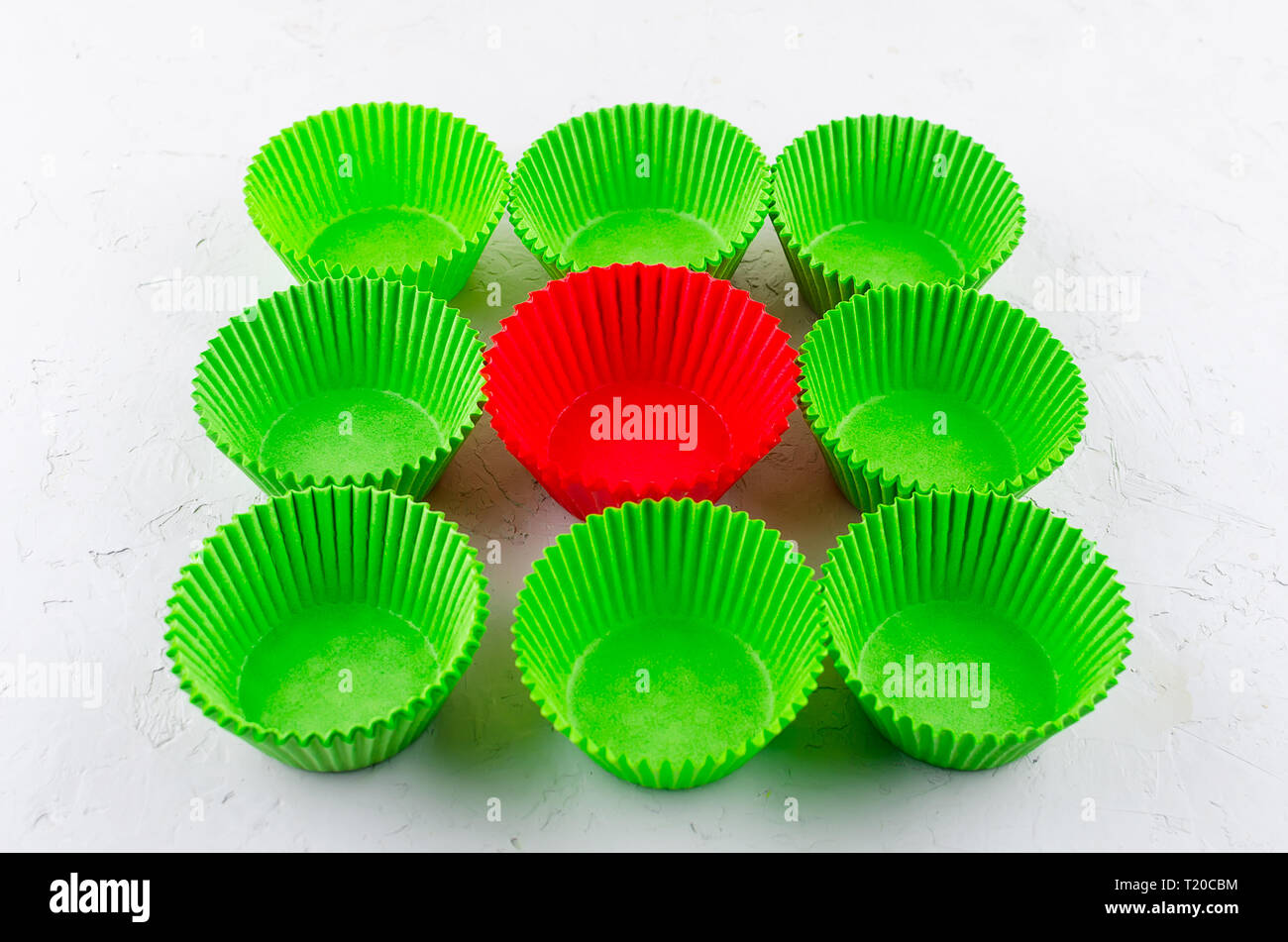 Brightly green and red colored paper baking cups for cupcakes or muffins on light grey conkrete background, copy space Stock Photo
