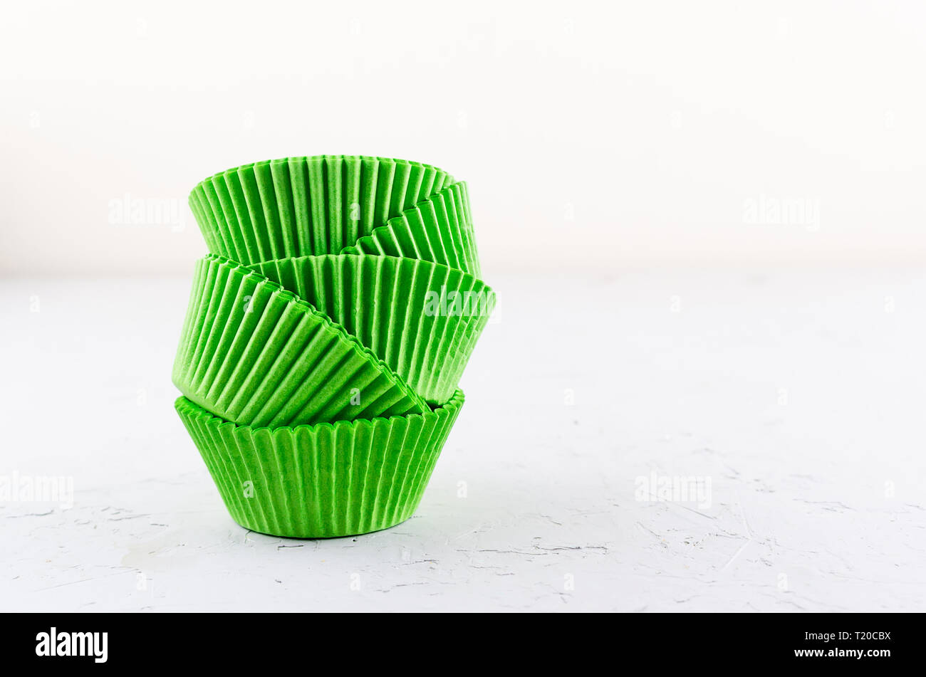 Brightly green colored paper baking cups for cupcakes or muffins on light grey conkrete background, copy space Stock Photo