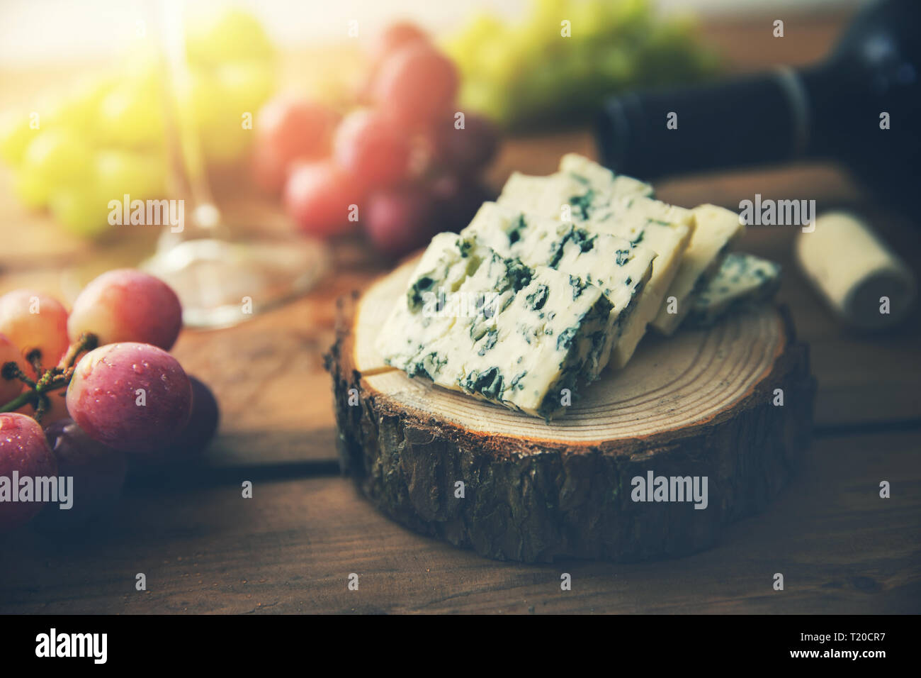 dor blue cheese on wood log slice with grapes and wine bottle Stock Photo