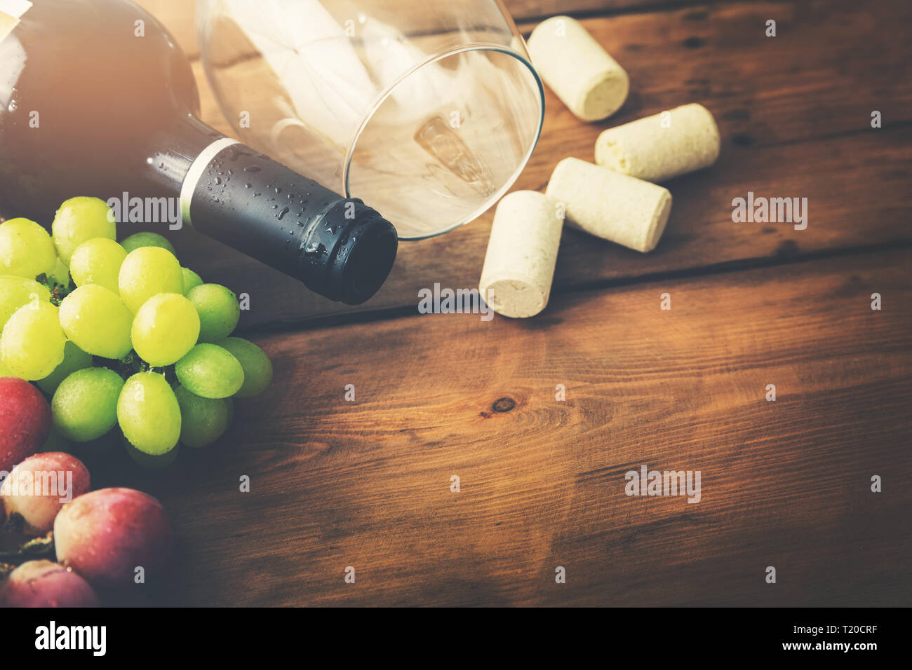 red wine bottle with glass and grapes on wooden background Stock Photo