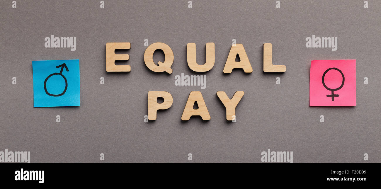 Equal Pay for man and woman, wooden words with gender symbols on gray background, panorama Stock Photo