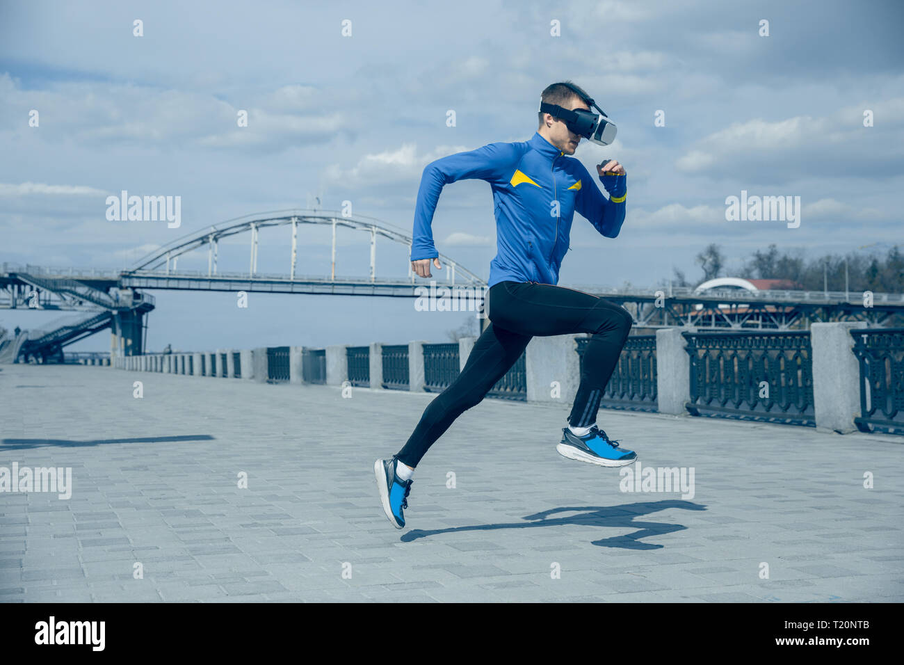 Man running on city background. Handsome athlete using VR glasses while runnig at morning. Healthy lifestyle and high tech concept. Stock Photo