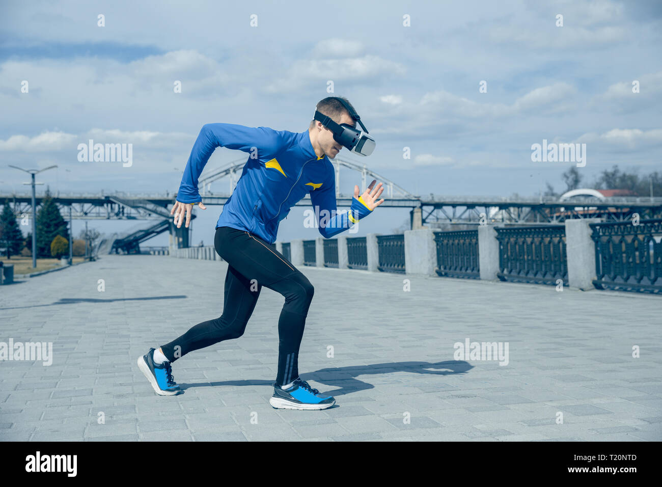 Man running on city background. Handsome athlete using VR glasses while runnig at morning. Healthy lifestyle and high tech concept. Stock Photo