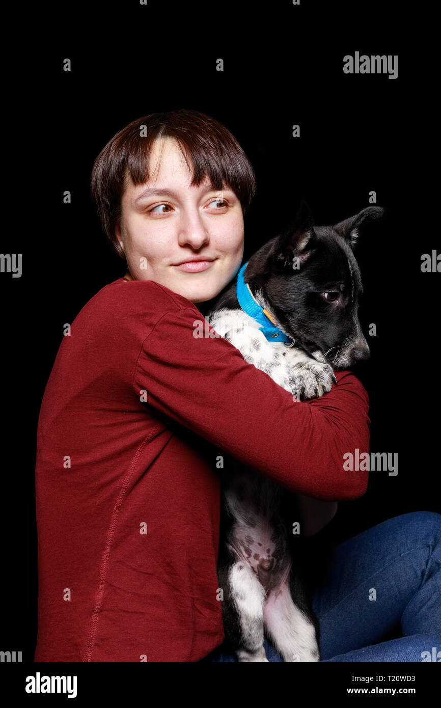 woman in red sweater hugging and holding mongrel dog in blue collar