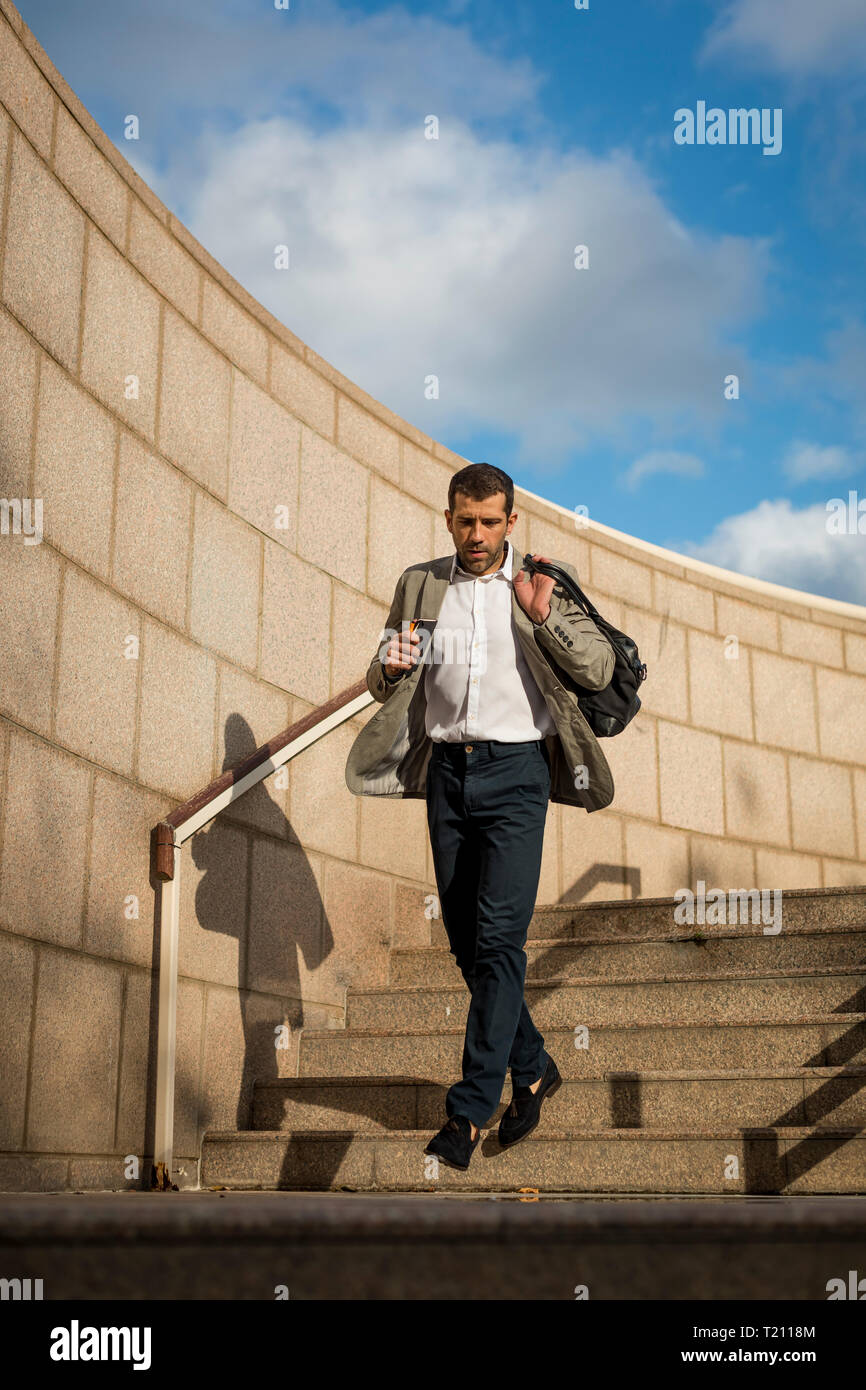 Businessman with bag walking downstairs Stock Photo