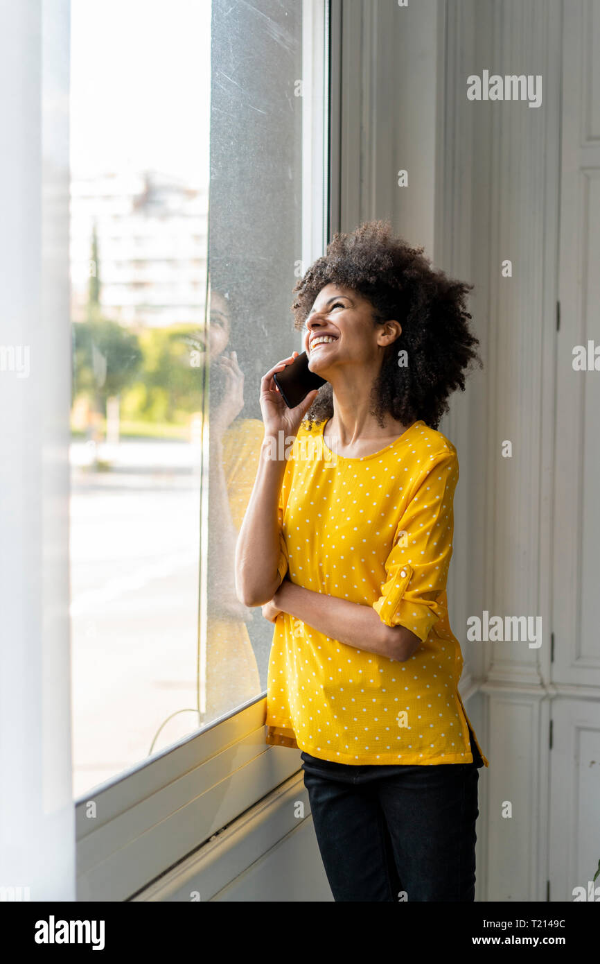 Woman standing at the window, talking on the phone Stock Photo