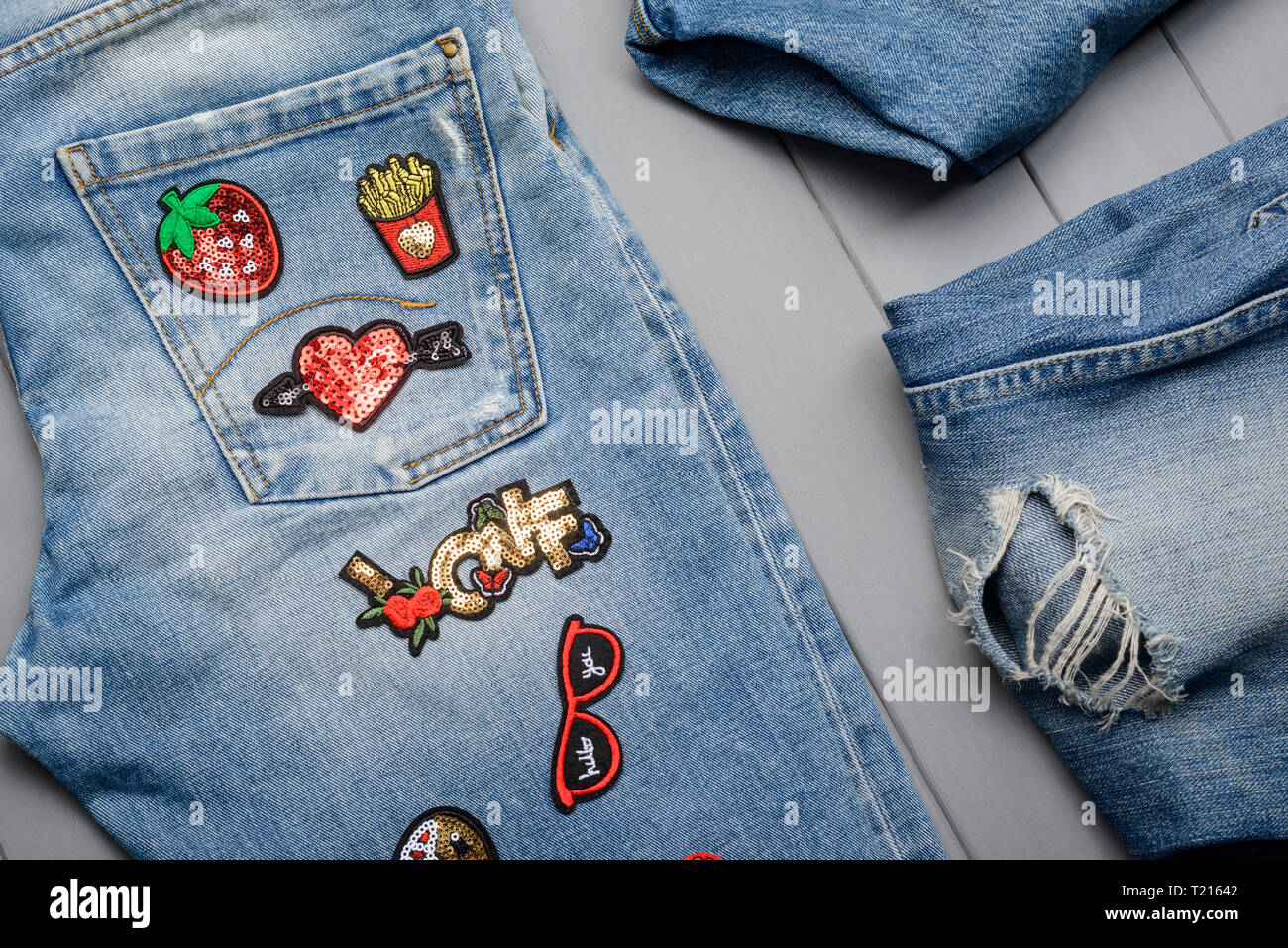 Sewing beautiful patches to jeans Stock Photo
