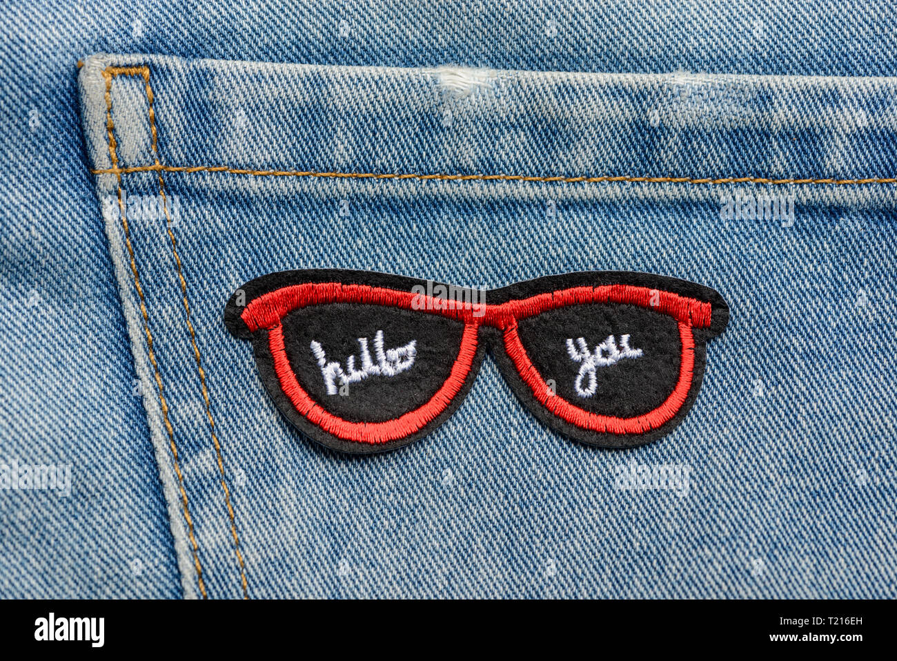 Red sunglasses embroidered patch on a pocket of jeans. Street fashion trends, stylish addition to casual denim. Stock Photo