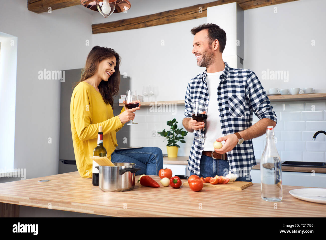 Affectionate couple in kitchen, preparing spaghetti toghether, drinking red wein Stock Photo