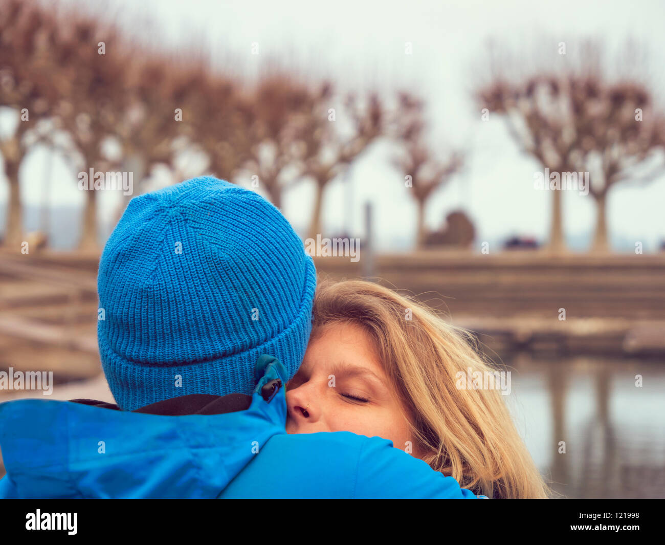 Man with blue woll cap embracing blond woman Stock Photo