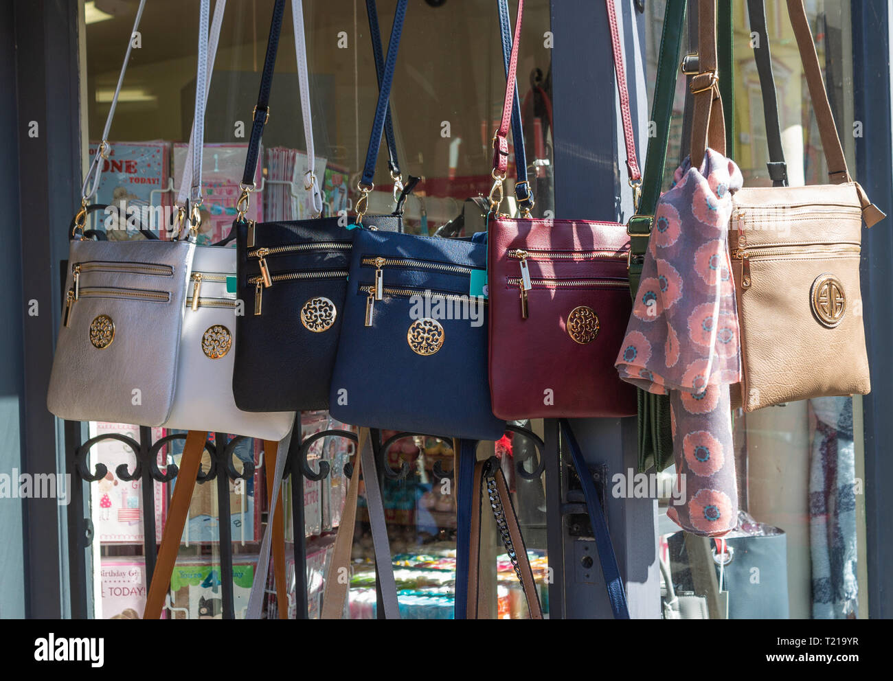 leather handbags hanging on display in shop window. Stock Photo