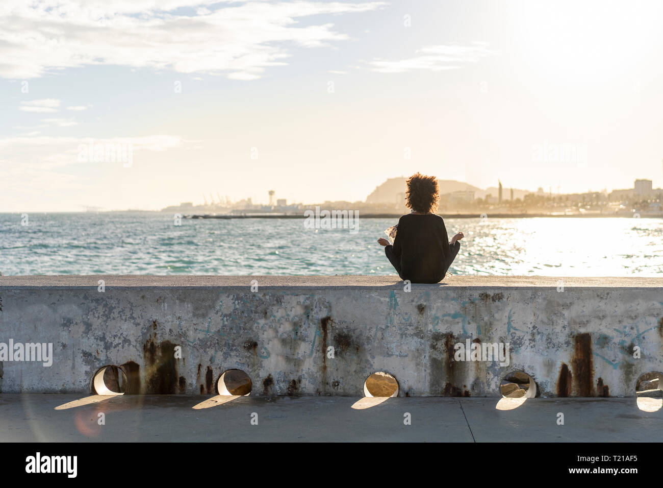 Back view woman sitting on wall hi-res stock photography and images - Alamy