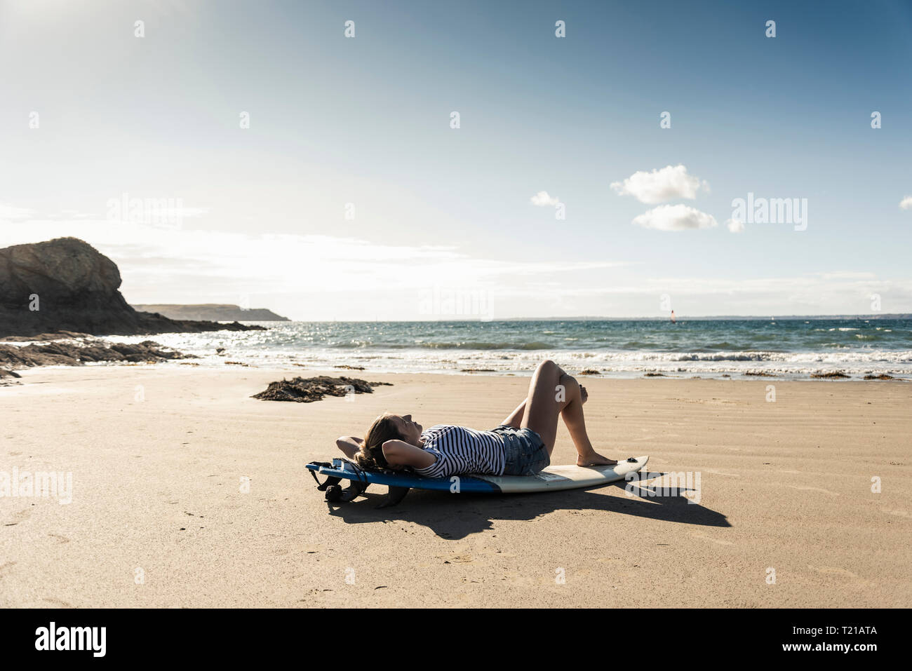 Young woman on the beach, relaxing on surfboard Stock Photo