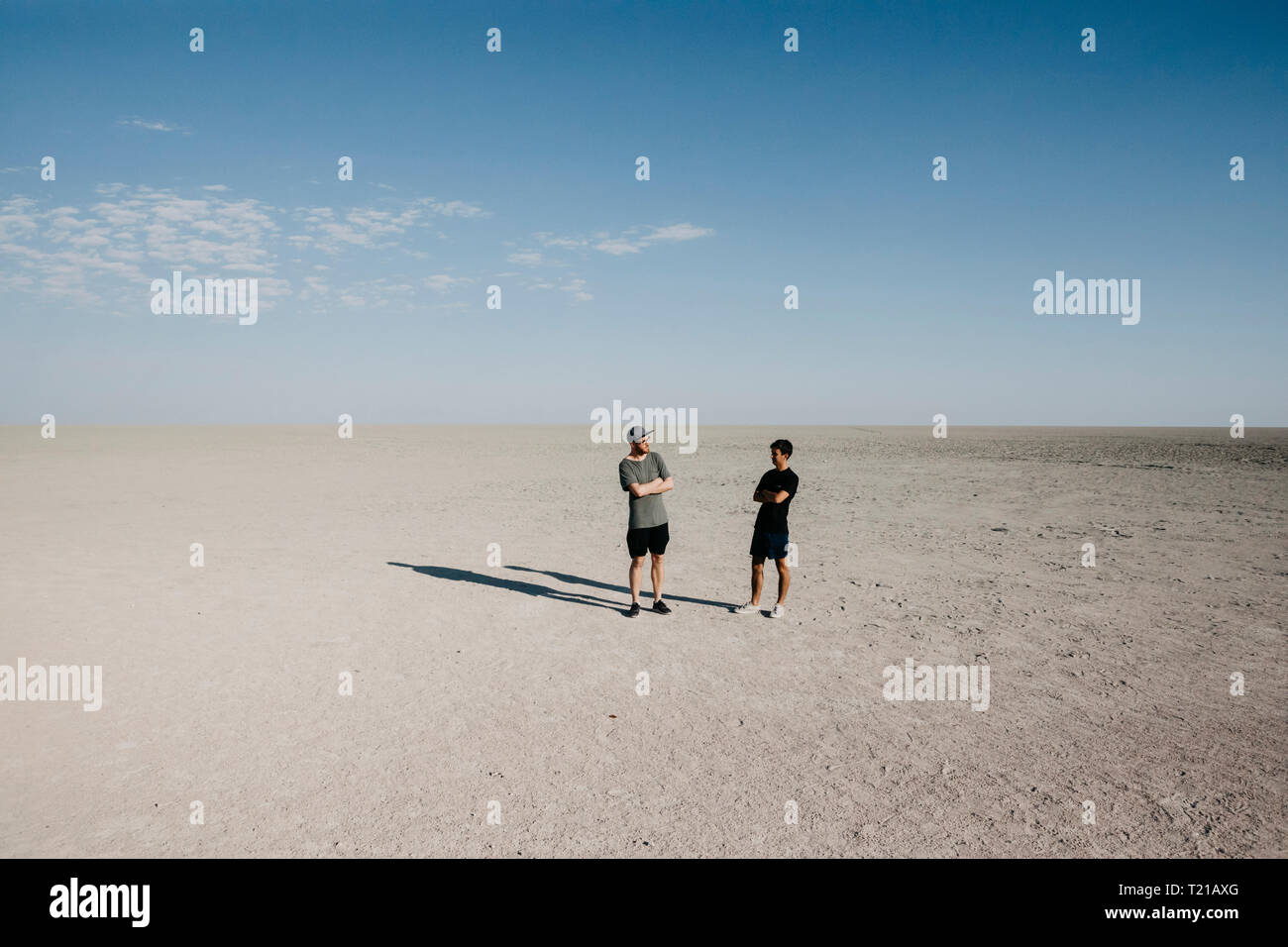Two young man standing in the desert, with arms crossed Stock Photo