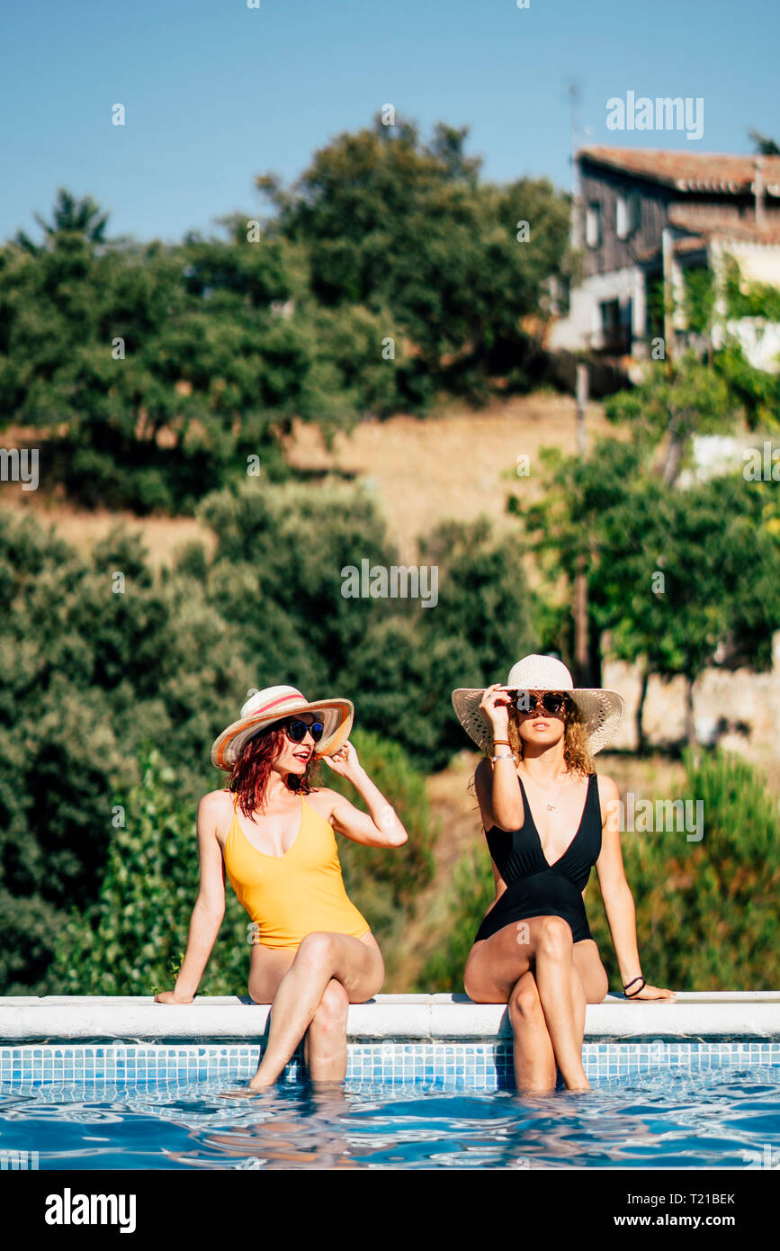 Two women in  swimsuits, sunbathing at the pool side Stock Photo