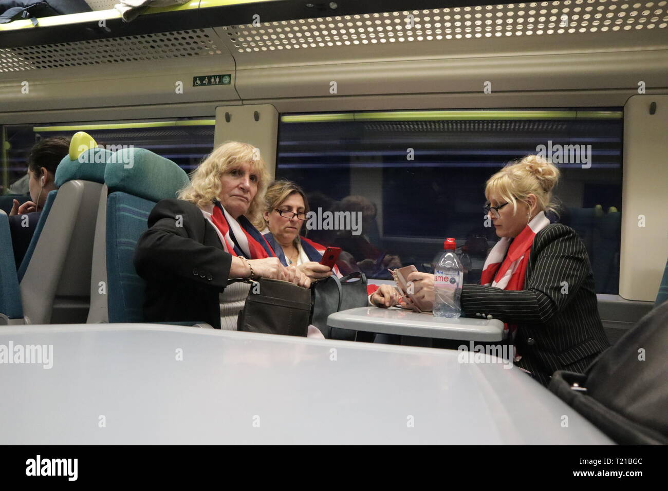 3 women wearing Union Jack flags on a train after vote on Brexit on 29 March 2019 Stock Photo