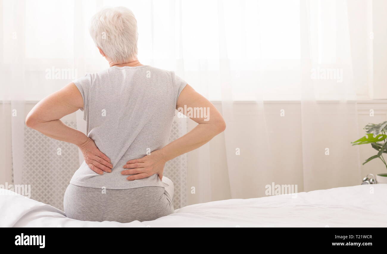 This bed isn't comfortable for me. Senior woman holding her painful