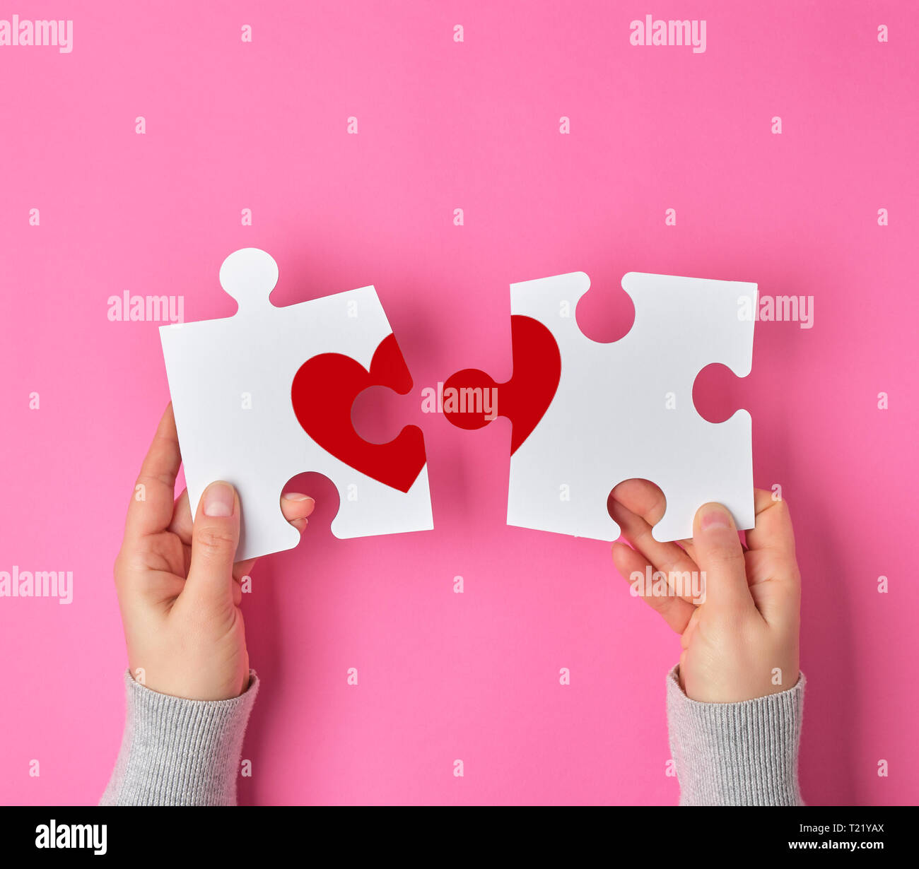 Female hands hold big white puzzles with a piece of red heart, pink ...