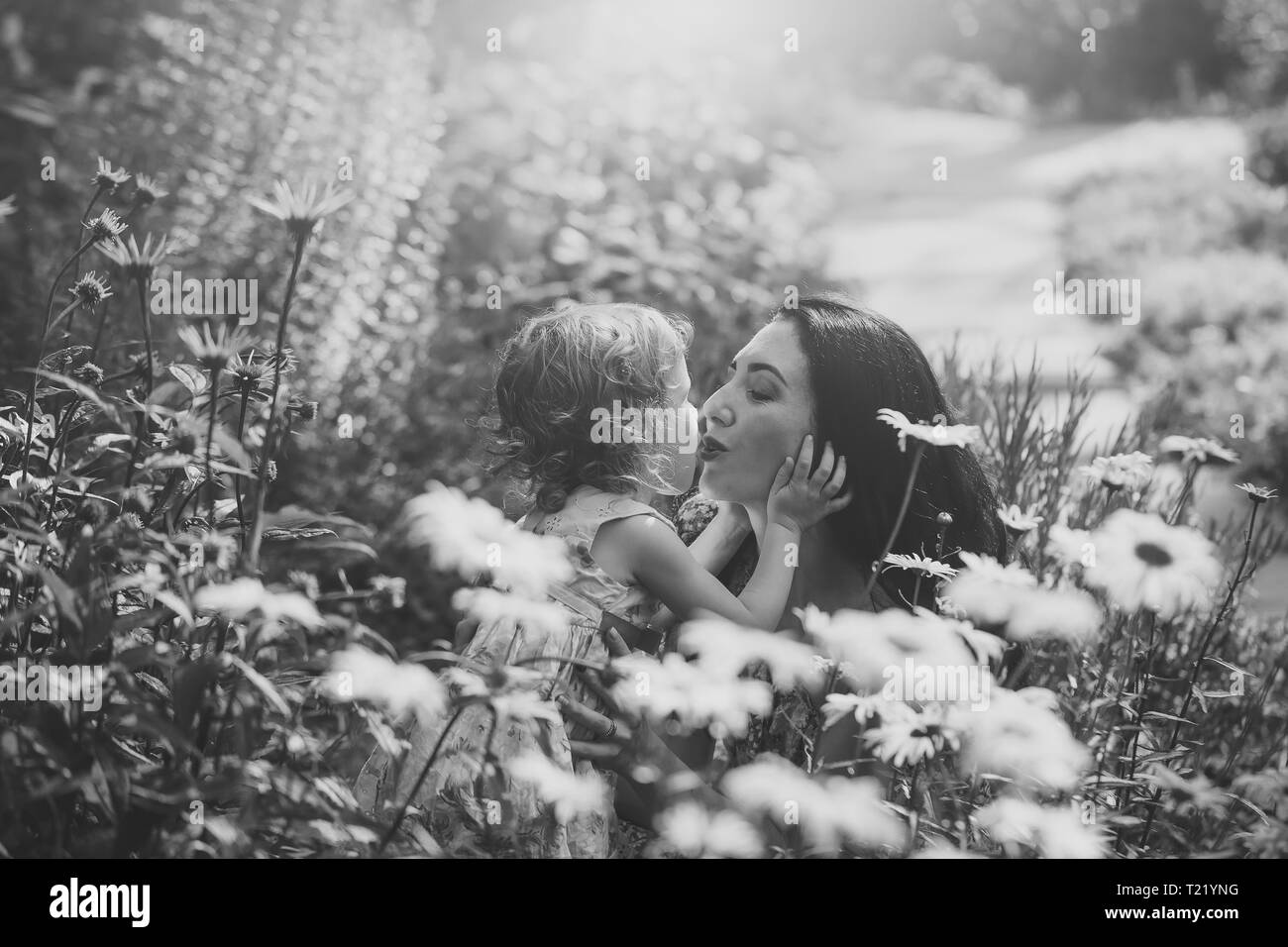 Woman and child kiss on sunny floral landscape Stock Photo
