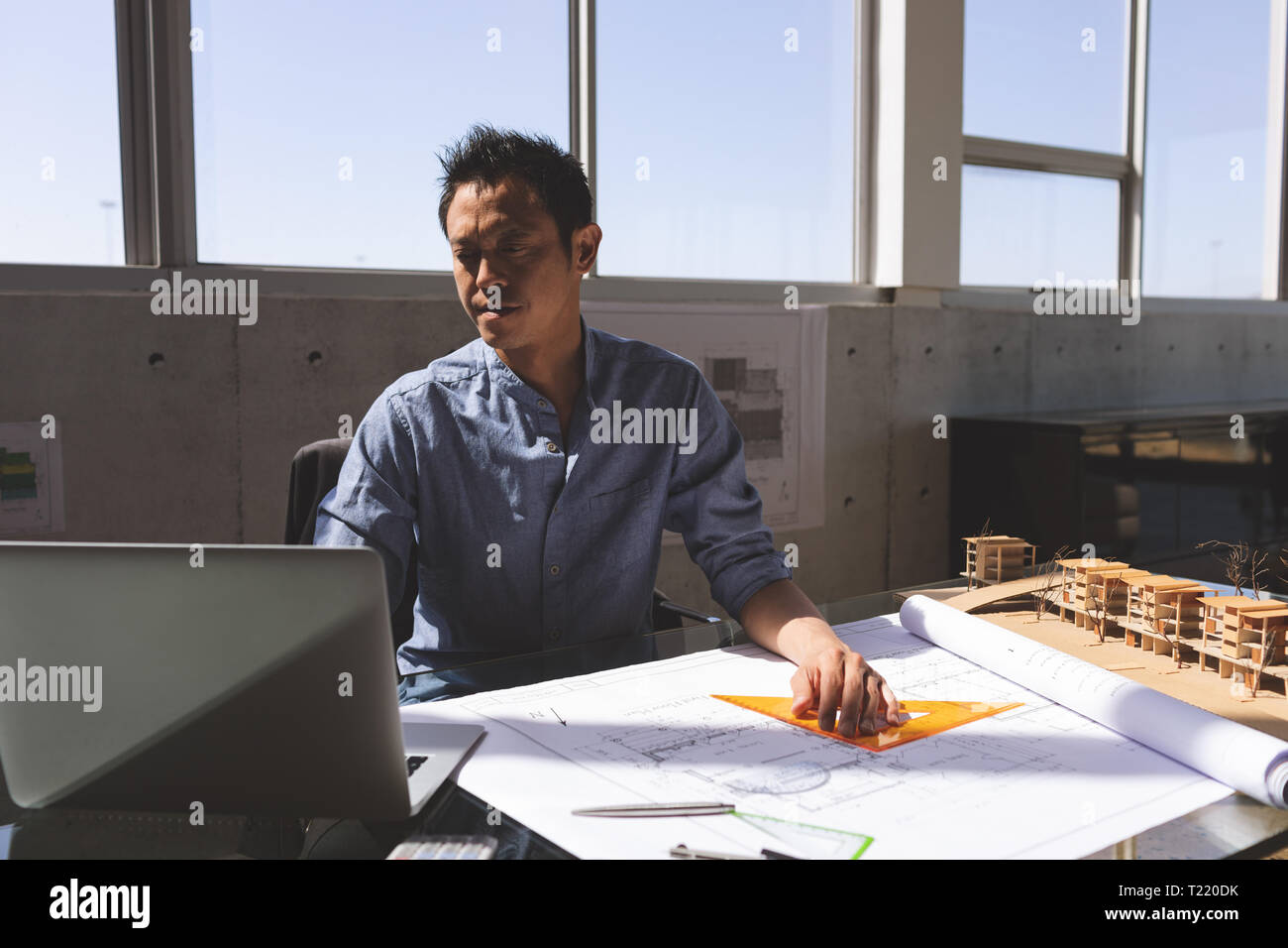 Male architect using laptop while working on blueprint Stock Photo