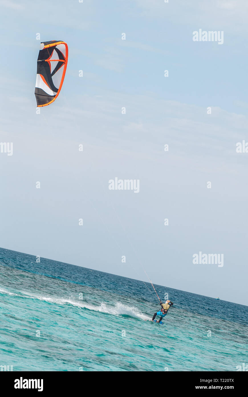 professional kiter glide the water surface of the ocean at great speed. Back view behind extreme wide shot Stock Photo