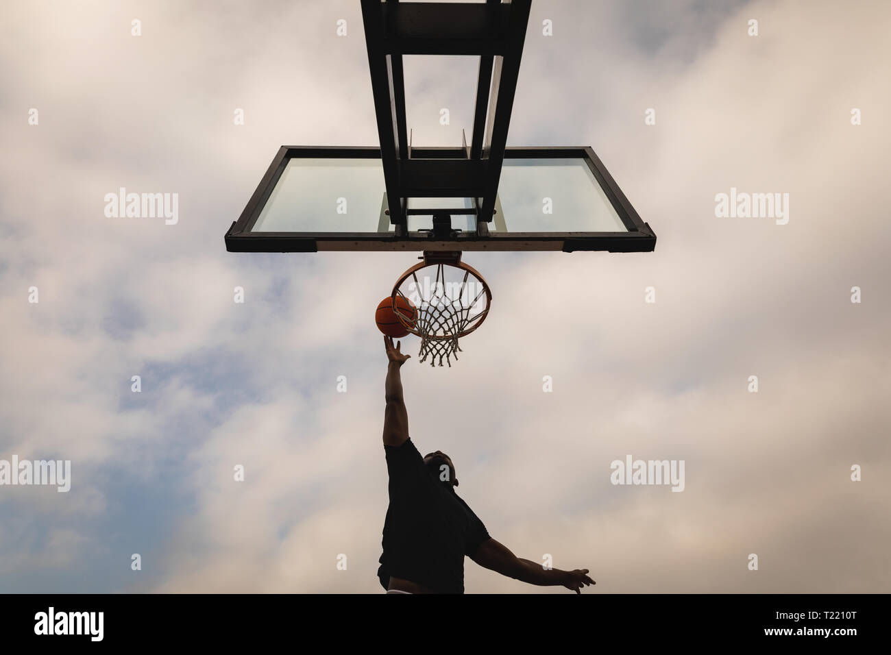 Man playing basketball while is putting the ball in basketball hoop