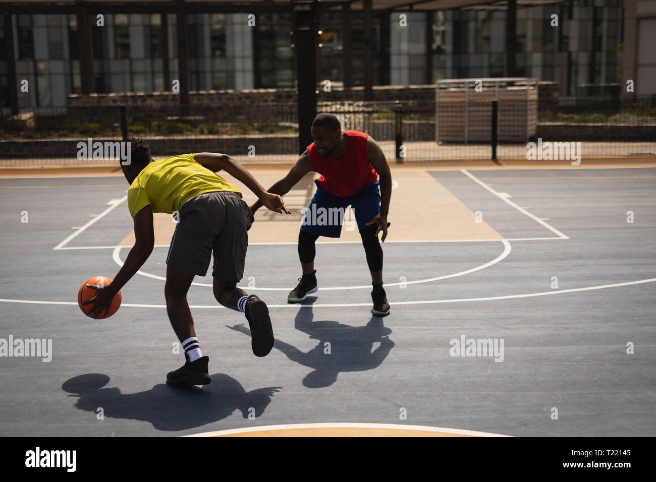 African basketball players dribbling another player on basketball court