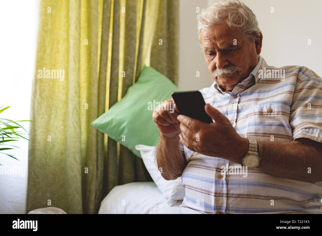 Senior man using mobile phone at nursing home Stock Photo