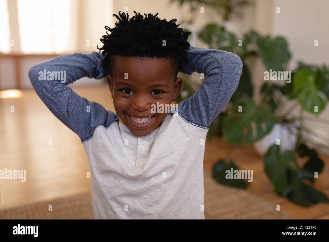 Happy cute boy standing with hands behind head at home Stock Photo - Alamy