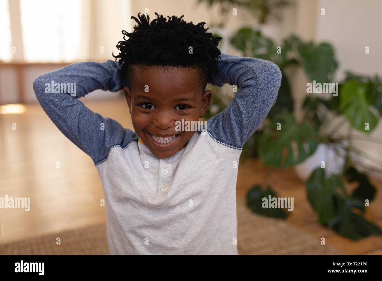 Happy cute boy standing with hands behind head at home Stock Photo