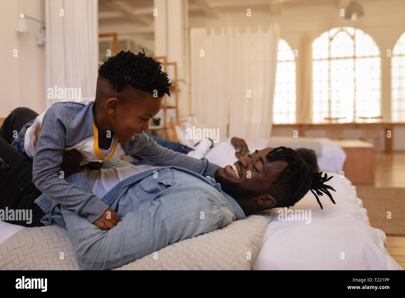 Father and son enjoying while lying on bed at home Stock Photo