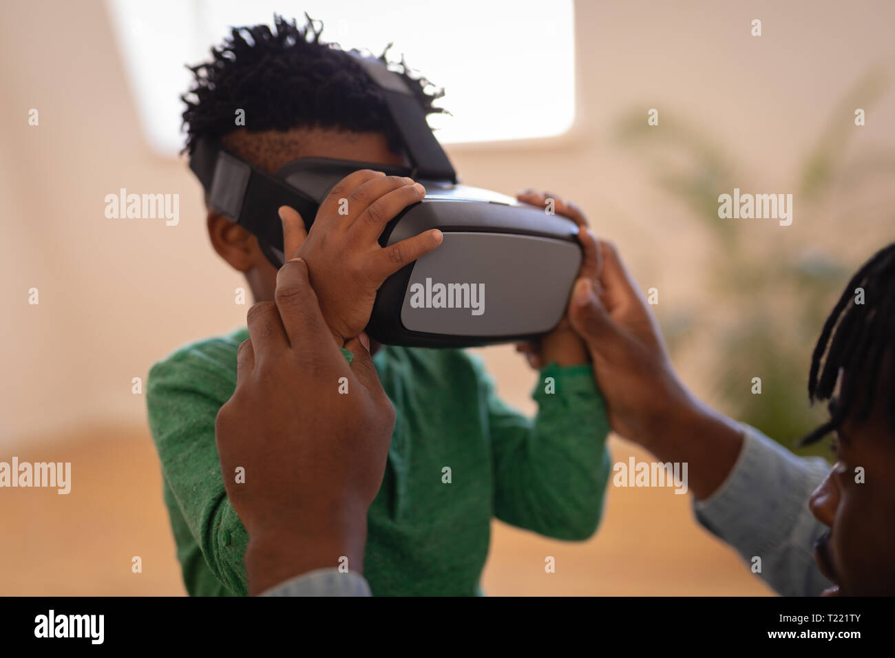 Father assisting his son to use virtual reality headset at home Stock Photo
